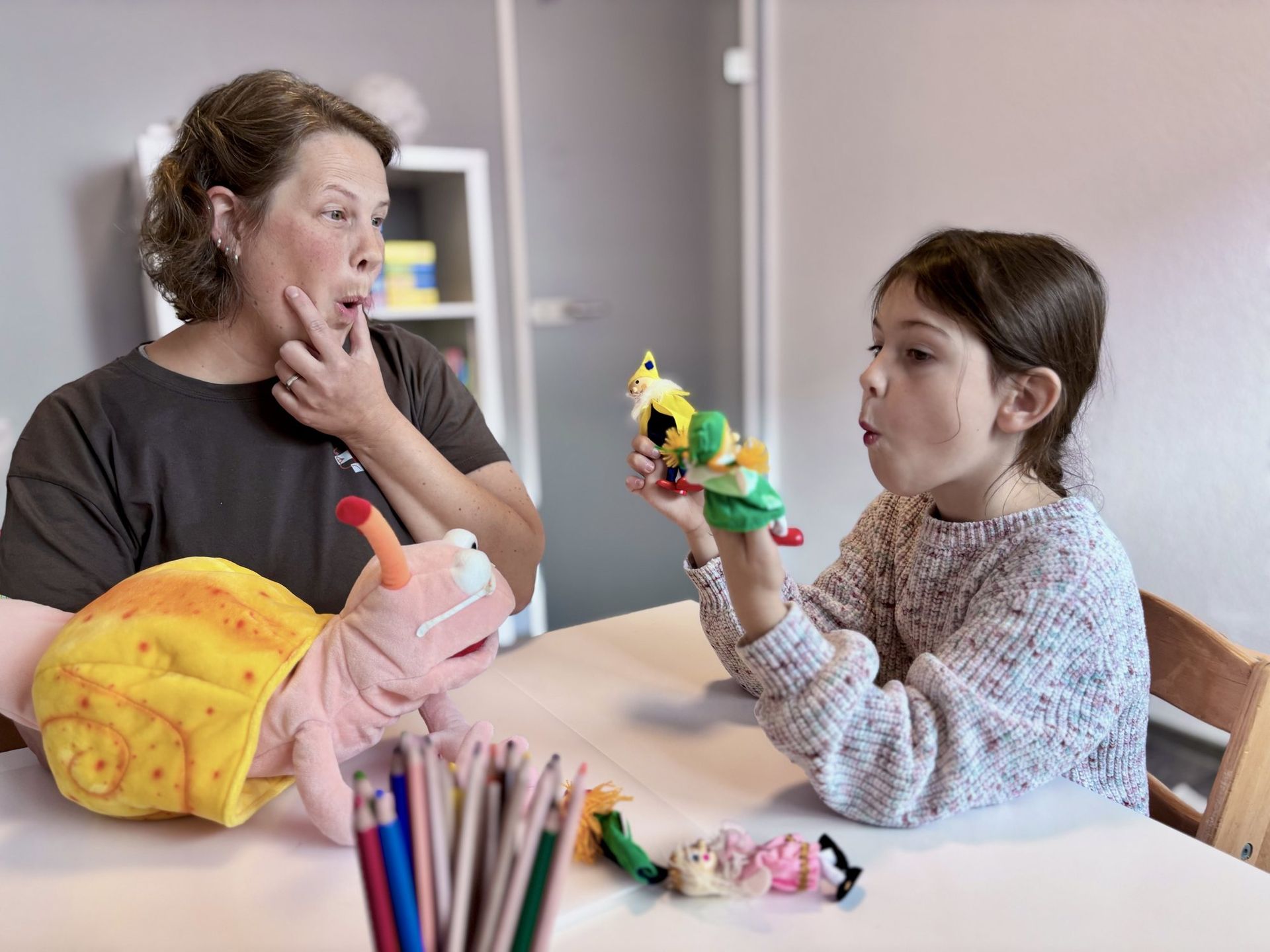 Mundmotorik-Übung mit Handpuppen zwischen Logopädin und Kind