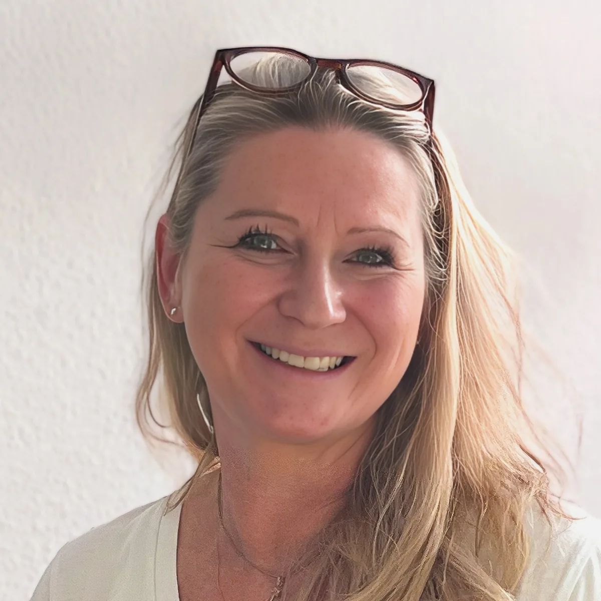 Portrait von Dorothee Wieden, Dipl.-Logopädin und Praxisinhaberin, lächelnd vor einer hellen Wand